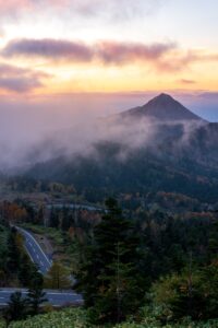 A mountain peak rising above mist-filled forested slopes at dawn in central Japan, fine art landscape by Mitsuki