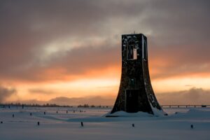 A weathered stone tower standing alone on a snowy plain under a dramatic cloudy sunset in central Japan, fine art landscape by Mitsuki